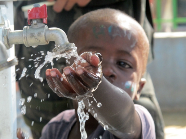 Criança negra pegando água em uma torneira