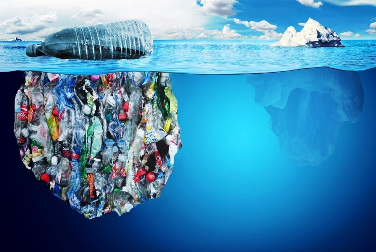 Mar azul com uma grande quantidade de plástico acumulado e uma garrafa plástica na superfície, como a ponta de um iceberg