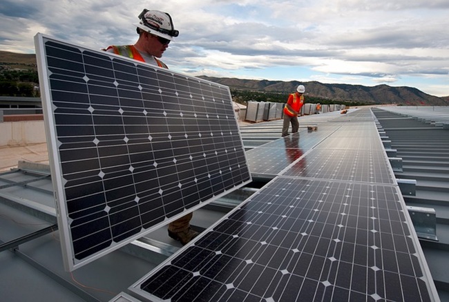 Dois trabalhadores instalam placas solares.